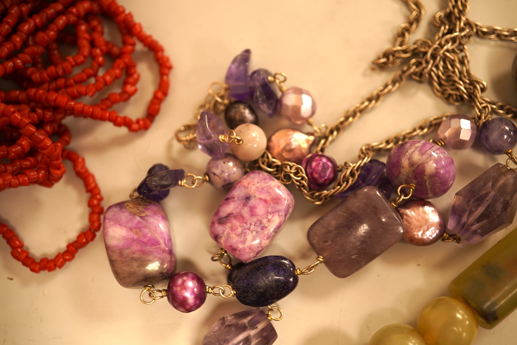 A small group of sundry jewellery including a simulated amber necklace and a multi strand coral bead necklace, etc.